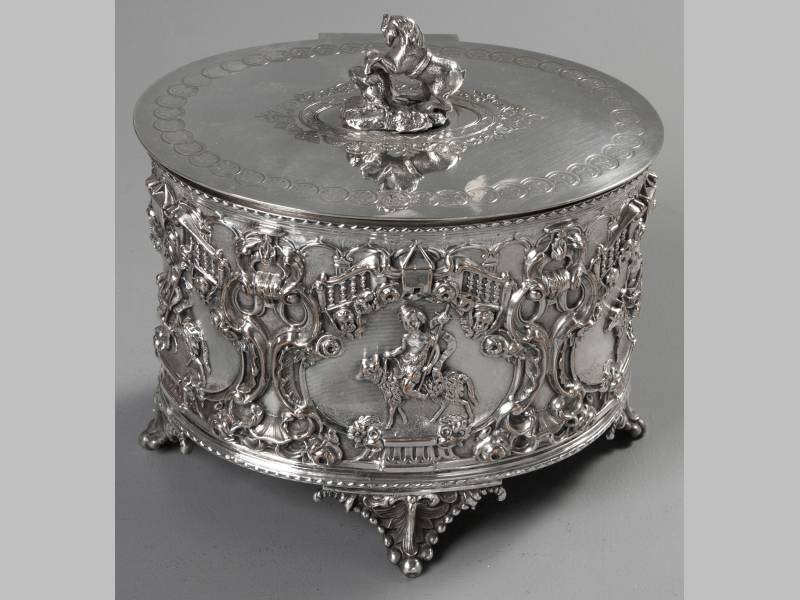 A CONTINENTAL SILVERPLATE COOKIE JAR, hinged cover of oval form engraved with fleur-de-lis and other