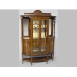 AN EDWARDIAN MAHOGANY DISPLAY CABINET, the astragal glazed doors flanked by bowed cupboards and