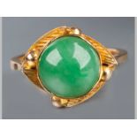 A 9CT YELLOW GOLD JADE RING, domed jade set in an organic yellow gold frame, ending on a solid