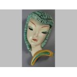 A GOLDSCHEIDER TERRACOTTA ART DECO WALL MASK, lady with light blue spiral curls, yellow collar,