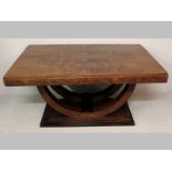 A 1930'S MAHOGANY ART DECO TABLE, the flamed top with a broad frieze, standing on stylized gimbles