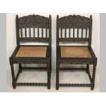 A PAIR OF COLONIAL EBONY CHAIRS, the top-rails and splats heavily carved with foliage and barley