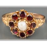 A 9CT YELLOW GOLD GARNET AND PEARL RING, centre pearl surrounded by eight garnets in floral form,