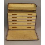 AN EARLY 20TH CENTURY TRAVELLING CHEST OF DRAWERS, covered in lacquered canvas, bound with oak