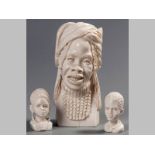 A CARVED IVORY BUST OF AN AFRICAN WOMAN, wearing a head scarf, 20cm high. Together with two