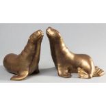 A PAIR OF BRASS SCULPTURES OF SEALS, realistically moulded, 33cm high, 32cm wide, (2).