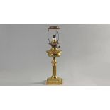 A VICTORIAN BRASS LAMP, converted to electricity, the gadrooned reservoir above a reeded column,