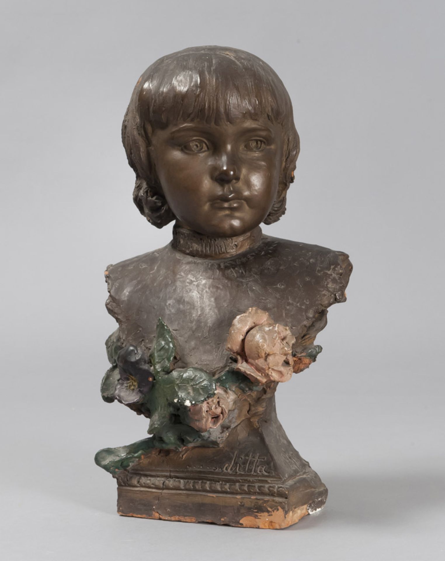 YOUNG GIRL'S BUST IN EARTHENWARE, EARLY 20TH CENTURY enamaled to fake bronze, with flowers in relief