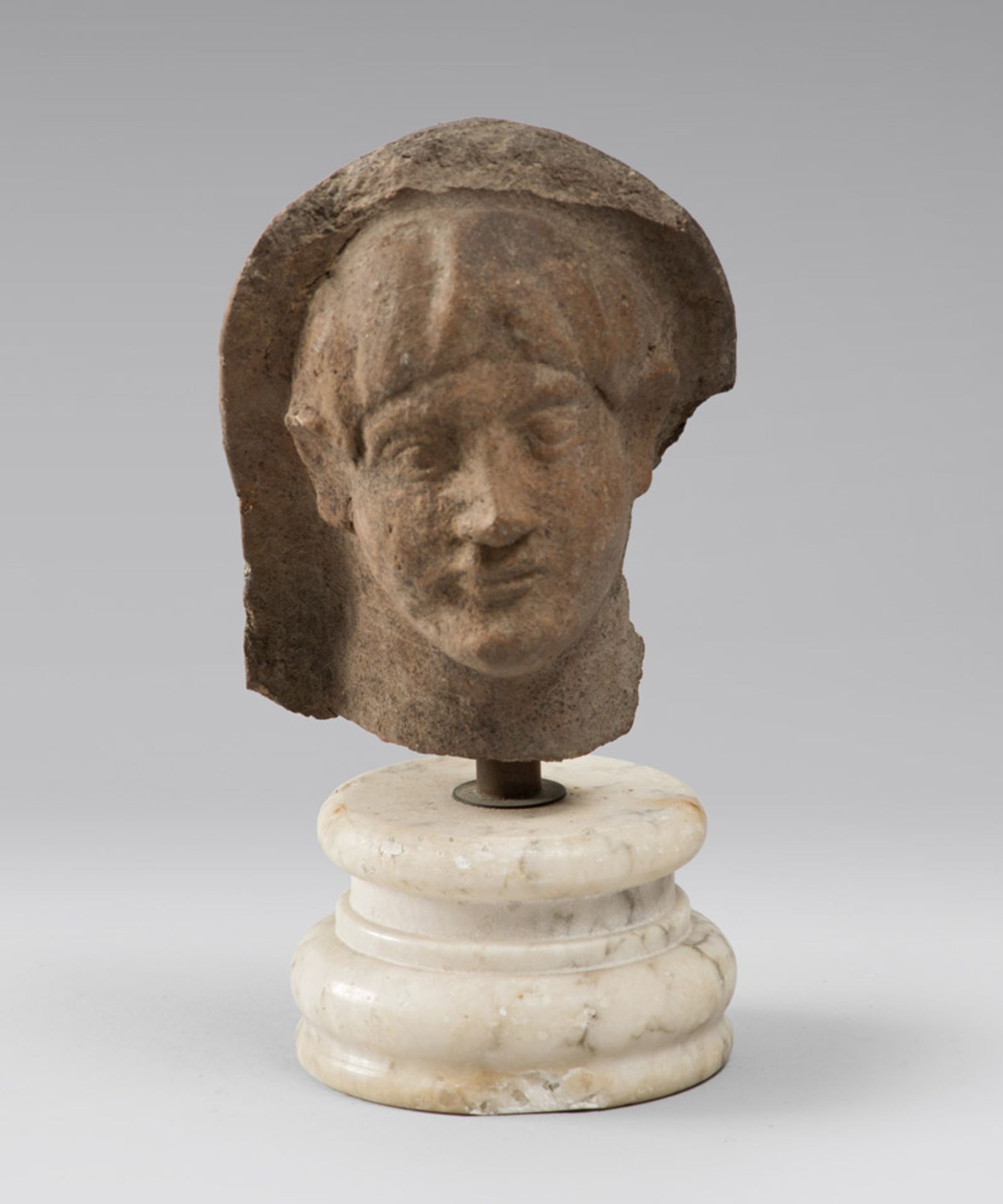 A VOTIVE MALE HEAD, 4TH, 1ST CENTURY B.C. Brown earthenware. Oval face, well-defined eyes, very