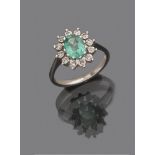 RING in white gold 18 kts., daisy shape, decorated with central emerald and contour of diamonds.