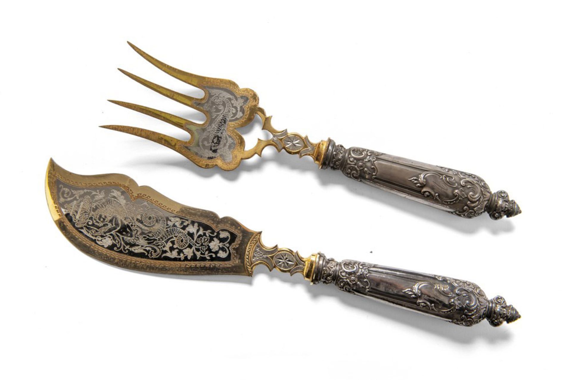 TWO GILDED SERVING PIECES, EARLY 20TH CENTURY with blades engraved to vegetable motifs. Length cm.