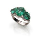 ATTRACTIVE RING in white gold 18 kts., to dome, embellished with three central emeralds oval cut and