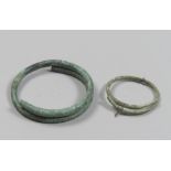 TWO ETRUSCAN BRONZE ARMILLS, 8TH-6TH CENTURY B.C. Rod with a smooth circular section that wraps