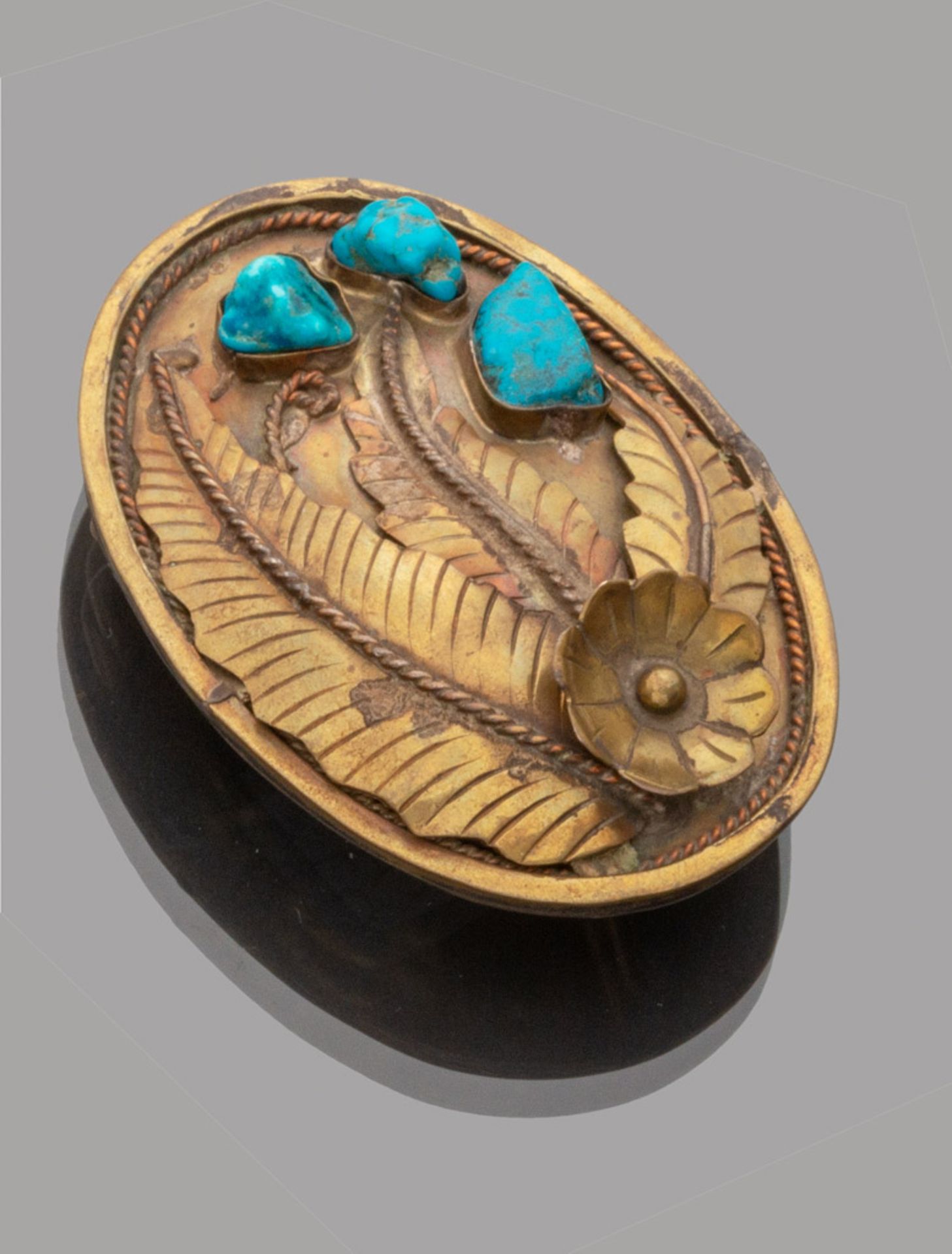 BUCKLE IN BRASS, 1950S oval shape with three turquoise stones and palm bas-relief. Measures cm. 9