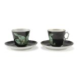 A PAIR OF PORCELAIN CUPS, 19TH CENTURY with saucers, polychrome decorated with leaves on black