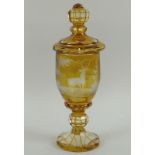 A Bohemian amber stained goblet and cover, engraved with two deer in a forest,