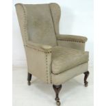 An Edwardian wing armchair, with cabriole front legs,