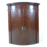 An early Victorian bowfront mahogany and line inlaid corner cupboard,