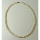 A string of ivory coloured pearls with 14ct gold clasp, by Honora, in original box.