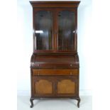 A late Edwardian bureau bookcase, drum action revealing fitted interior with drawer surface,