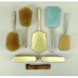 A yellow enamel and silver dressing table set, comprising two hairbrushes,