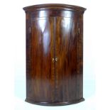 A George III mahogany and line inlaid barrel fronted corner cupboard,