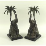 A pair of modern bronze candlesticks, in the form of seated elephants and palm,