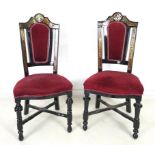 A pair of Victorian ebonised style chairs, 20th century, with curved frames and inlaid with brass,