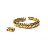 A gold bracelet, in an interwoven link design, on a snap clasp, with foldover safety catches,