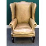 A George II style wing armchair, with studded light tan leather upholstery,