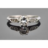 A platinum and diamond ring, claw set with the principal circular cut diamond at the centre,