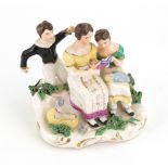 An English porcelain group, circa 1830, modelled as a mother holding an open book,