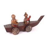 A wooden Japanese Kobi toy of a boat with wheels with two figures on board,