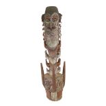 A tribal carved wood sculpture, surmounted by two faces above a carved section and circular base,