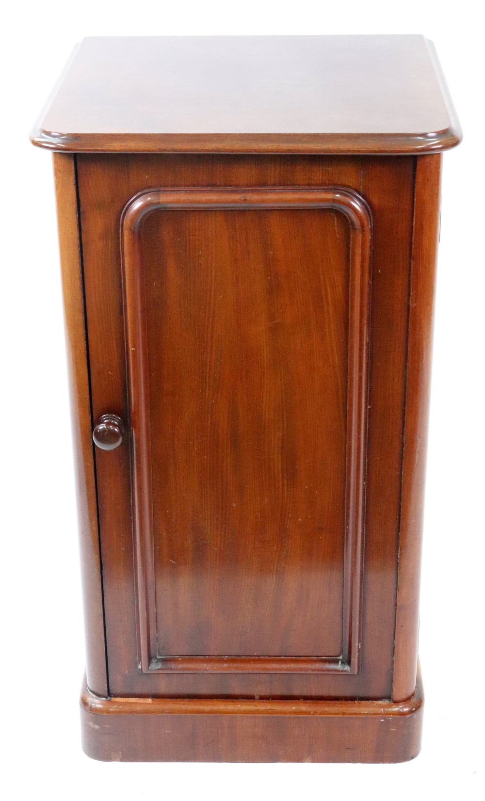 A Victorian mahogany pot cupboard, circa 1860, enclosed by a panelled door, on a plinth base,