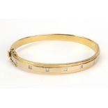 A two colour gold and diamond set hinged bangle,