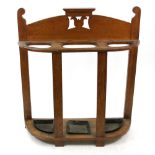 An Art Nouveau oak stick stand, the shaped and pierced back above three divisions, 85cm wide.