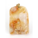 A carved mottled yellow jade pendant depicting a prowling lion and flowers,