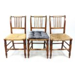 A set of three George III country elm dining chairs, with reeded stick backs and rush seats,
