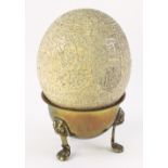 An ostrich egg, carved with alternate panels of animals including a cat,