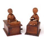 Two carved wooden Japanese Kobi toys, one playing a drum which, when the handle to rear is turned,
