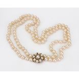 A two row necklace of uniform cultured pearls, on a 9ct gold, cultured pearl and diamond set clasp,