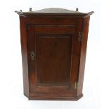 A George III oak corner cabinet, enclosed by a raised and fielded panel door, 68cm wide.