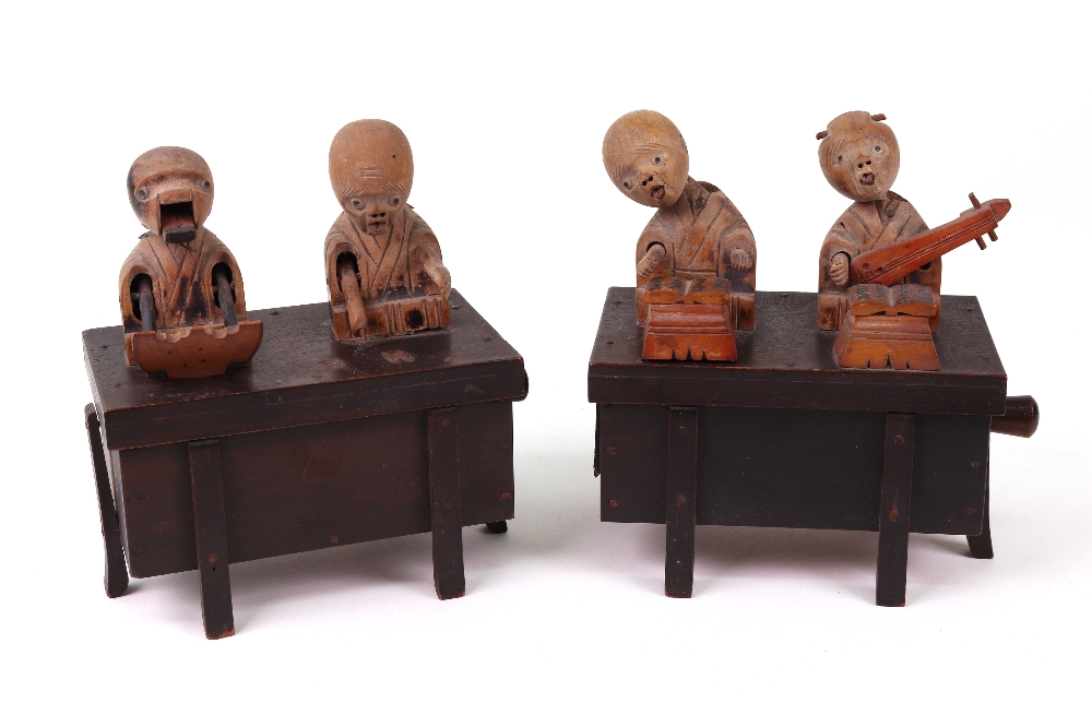 Two carved wooden Japanese Kobi toys, both with two figures on top of a box,