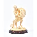 A Japanese carved ivory figure of a fisherman, Meiji period, holding a basket of fish and turtles,