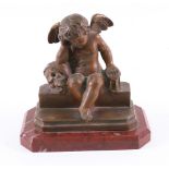 A French late 19th century bronzed figure of a cherub, one arm resting on a skull, seated on a step,