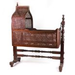 A half size model mahogany cot, in late Regency style, with arched hood and cane panel sides,