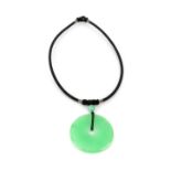 A green jade pi disc pendant on woven cord necklace.