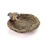 An Austrian cold painted bronze figure of a goldfinch perched on the edge of a nest,