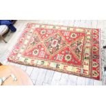 A modern Caucasian style rug, with red ground and hooked lozenge with polychrome scroll border,